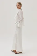 Blusa blanca de gasa con lunares, escote en V con volados y mangas largas acampanadas.