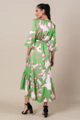 Vestido midi cruzado de satén estampado en tonos verde, blanco y rosa. Tiene lazo en la cintura, mangas 3/4 acampanadas y falda irregular con volados.