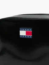 Cartera tipo bandolera de Tommy Jeans con acabado brillante y liso. Presenta un compartimento principal con cierre de cremallera y una insignia con el logo de la marca en la parte frontal. Incluye una correa ajustable.