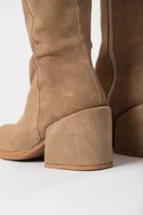 Bota bucanera de caña alta color visón, confeccionada en cuero descarne, con cierre lateral y taco cuadrado forrado.