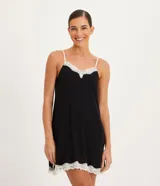 Camisón corto negro de viscolycra, con breteles finos blancos y escote en V decorado con encaje blanco y un pequeño lazo al centro. Presenta detalles de encaje blanco en el ruedo.