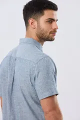 Camisa de manga corta confeccionada en mezcla de lino y algodón, color beige, con cuello camisero abotonado, bolsillo frontal en el pecho y cierre de botones.