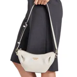 Bolso de hombro Guess modelo Amorette, color beige claro (marfil/taupe), con diseño plisado y textura de cuero sintético. Presenta herrajes y logo frontal en tono dorado. Incluye correa ajustable y removible para llevar al hombro o cruzada.