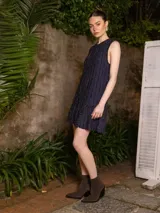 Vestido corto negro con lurex, sin mangas, con volados en el ruedo y corte recto.