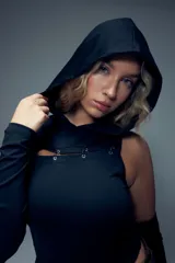 Body negro con capucha, manga larga en un lado y manga corta en el otro. Presenta un corte en el pecho con detalles de argollas metálicas.