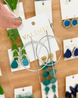 Aros colgantes plateados con forma circular y detalle de barra vertical.