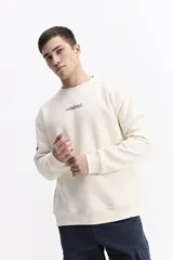 Buzo de algodón color crema, corte oversize, con escote redondo y puños. Presenta un estampado gráfico grande en la espalda con un globo aerostático y texto que incluye "SOME PEOPLE MIGHT THINK I'M WEIRD BUT, I DON'T CARE" y otros símbolos gráficos.