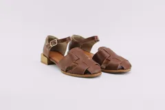 Sandalias de cuero color marrón, estilo huarache, con puntera cerrada de corte almendrado, tira ajustable con hebilla en el tobillo y taco cuadrado bajo con acabado símil madera.