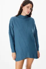 Sweater de punto color azul, con cuello alto y diseño de espiga calada en el frente. Presenta mangas largas con puños ajustados y un corte holgado.