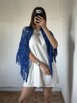 Chal tejido artesanalmente en cinta color azul, con diseño de red abierta y flecos en los bordes.
