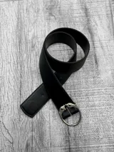 Cinto negro de cuero sintético con hebilla metálica plateada con diseño de dos cabezas de tigre enfrentadas formando un círculo.