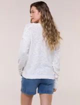 Cardigan blanco de punto liviano y texturado, de corte holgado y diseño casual. Cuenta con escote en V pronunciado, abotonadura frontal, mangas largas con hombros caídos y bolsillos delanteros tipo parche.
