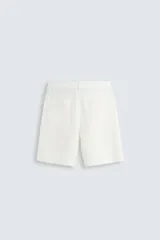 Bermuda de algodón color blanco, de corte relajado, con cintura elástica, bolsillos frontales y bolsillos traseros de plastrón. Cierre frontal con cremallera y botón.