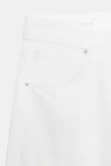Jeans blancos de tiro medio con cinco bolsillos, detalle de costuras torcidas y cierre frontal con cremallera y botón metálico.