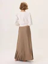 Falda larga color marrón, con diseño de corte asimétrico y tablas en el ruedo que aportan movimiento. Confeccionada en una mezcla de algodón y tencel.