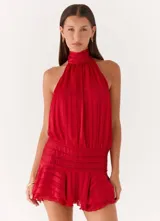Vestido corto de satén rojo con diseño de cuello halter, cuerpo holgado y falda con volados y cintura elástica fruncida.
