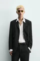 Blazer de corte relajado confeccionado en una mezcla de viscosa y lino. Presenta cuello con solapas de muesca, cierre frontal de tres botones, bolsillo de vivo en el pecho y tres bolsillos con solapa en la cadera. Incluye aberturas en la espalda y medio forro interior.