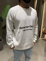 Sweater de tejido de punto color blanco con cuello redondo, mangas largas y puños acanalados. Presenta un estampado frontal en color negro con el texto 'Bohemian Dept' y 'Only Good News'.