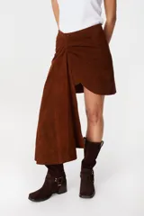 Falda de cuero marrón con diseño asimétrico, presenta un detalle de lazo frontal drapeado que crea una caída lateral más larga.