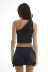 Top corto negro de un solo hombro, confeccionado en tela acanalada con brillo. Presenta apliques de tachas metálicas redondas en el ruedo inferior.