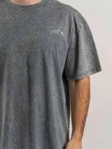 Remera de corte oversize color verde con efecto lavado, manga corta y cuello redondo. Presenta un estampado gráfico en la espalda con el diseño de una montaña y la frase 'Fresh air is free, don't be afraid of the high'.
