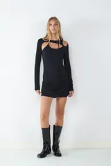 Vestido mini negro de manga larga con diseño ceñido, detalles cut-out en el pecho y los hombros, y lazos ajustables.