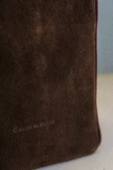 Bolso tipo matera de diseño vertical, confeccionado en una combinación de cuero liso color bordó y gamuza color marrón chocolate. Cuenta con doble asa superior y un bolsillo frontal abierto.