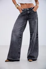 Pantalón de jean estilo wide leg en color negro con efecto lavado. Presenta un corte holgado, tiro medio y costuras reforzadas a lo largo de las piernas, con un ruedo deshilachado y desgastado.