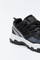 Zapatilla deportiva de estilo trekking con diseño técnico y urbano. Presenta una estructura combinada de paneles de malla y piezas de poliuretano, con sistema de cordones integrado y suela robusta con relieve para mayor estabilidad.