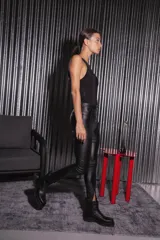 Pantalón negro de bengalina engomada, tiro alto, con cierre metálico frontal y corte en la botamanga.