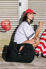 Bolso deportivo tipo duffel bag de nylon color verde oliva, con asas de mano y correa ajustable para llevar al hombro.