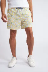 Short de baño con cintura elástica y cordón ajustable, confeccionado en tela ligera de secado rápido. Presenta un estampado botánico integral en tonos amarillos, blancos y azules, con dos bolsillos delanteros y uno posterior.