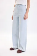 Pantalón jean de corte ancho y tiro alto, con estampa de rayas finas celestes y blancas, bolsillos laterales y cierre frontal con botón metálico.