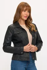 Campera de cuero sintético en color negro, con diseño tipo trucker, cuello clásico, cierre frontal con botones metálicos y bolsillos con solapa en el pecho.