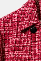 Blazer cruzado de tweed rojo con patrón texturizado en tonos blanco y negro, cuello con solapa, manga larga y cierre frontal con un botón.