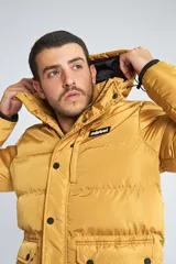 Campera puffer color mostaza con capucha, cierre frontal con botones y bolsillos laterales. Cuenta con logo de la marca en el pecho.