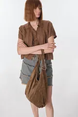 Bolso hobo de cuero gamuzado color marrón, con correa de hombro y cierre superior.