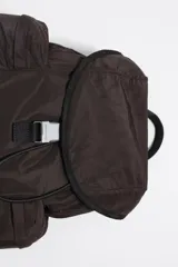 Mochila de nylon color marrón oscuro, con estructura blanda, cierre principal mediante cordón y solapa superior asegurada con hebilla de plástico gris. Posee dos bolsillos frontales con fuelle y asas ajustables.