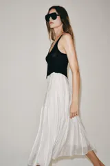 Falda midi de tiro medio de la colección ZARA Woman, confeccionada en mezcla de lyocell con acabado fluido y bajo en línea evasé. Cuenta con forro interior a tono y cierre lateral con cremallera oculta.