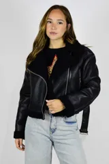 Campera de cuero sintético marrón con interior y detalles de corderito sintético blanco, cuello con solapas, cierre frontal y bolsillos con cremallera.