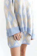 Sweater oversize con cuello en V y estampado de rombos en tonos lila, rosa y rojo. Tejido de lana artesanal.