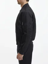Campera bomber negra Calvin Klein de satén de nailon reciclado, con cuello, puños y bajo de punto de canalé. Tiene cierre de cremallera, bolsillos de hendidura en la cintura, detalle de cremallera en la manga e insignia con el logo de goma de Calvin Klein en la manga. El forro y el relleno son de poliéster reciclado REPREVE®.