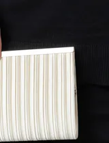 Cartera tipo clutch de Jessica McClintock, con diseño rectangular y acabado plisado en color crema. Cuenta con cierre superior metálico y estructura rígida.