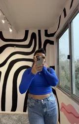 Polera de manga larga, cuello alto y corte crop, color azul Francia, confeccionada en lycra premium con un pequeño logo bordado en color rosa en el pecho.