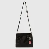 Bolso tipo tote mini de la marca Bubba, color verde oscuro, con doble asa de mano y correa larga ajustable y extraíble. Presenta el logo de la marca en el frente y un dije colgante con la letra B en color rosado.