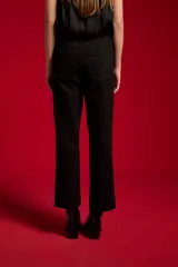 Pantalón jean negro de tiro alto y corte recto, con bolsillos clásicos y cierre frontal de botón y cremallera.