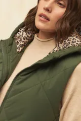 Chaleco largo marrón capitoneado con capucha, cierre frontal y bolsillos laterales. Forro interno de satén con estampado animal print.