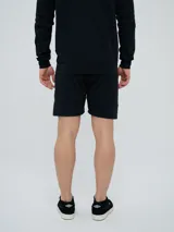 Bermuda deportiva Umbro modelo Terrace, color negro, con bolsillos laterales y detalles sutiles en el lateral.