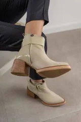 Bota corta color beige con estribo desmontable, cierre lateral y taco de madera.