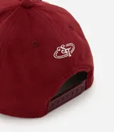 Gorra masculina de color bordó, confeccionada en tejido texturizado tipo gamuza, con visera curva, regulador y bordado frontal en lettering blanco.
